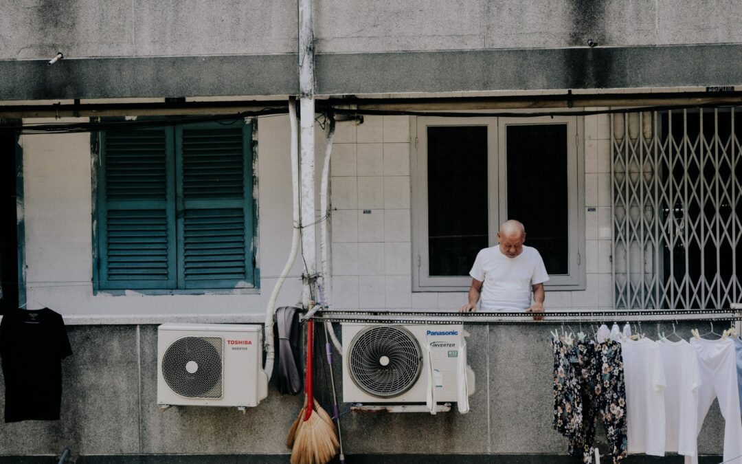 man looking down from apartment building, air conditioners out and exposed